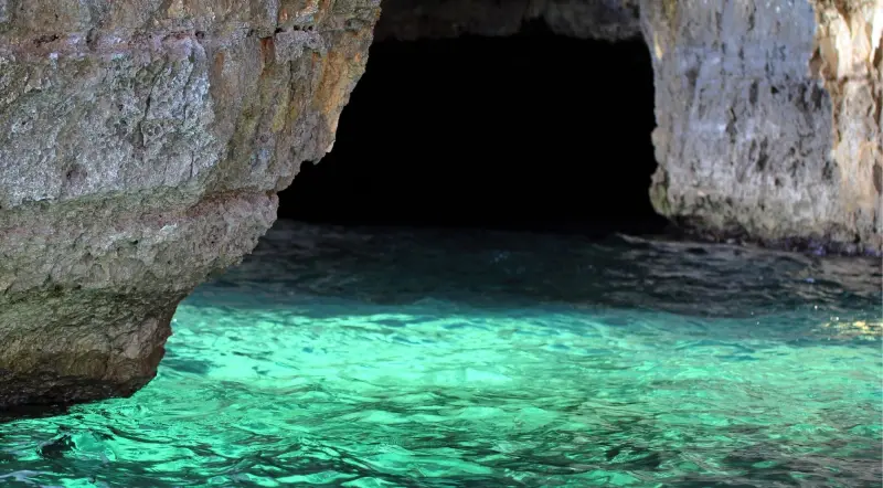 Clear emerald water at the dark entrance to the Blue Cave on the Lustica Peninsula