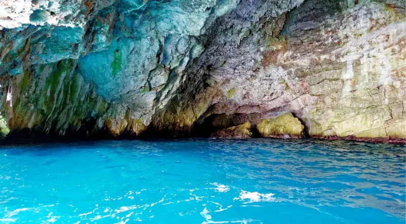 Glowing turquoise water inside the Kotor Blue Cave beneath the rock ceiling