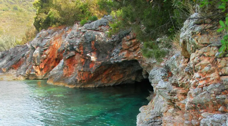 Rocky Lustica Peninsula coastline with a sea cave opening and green cliffs near Kotor